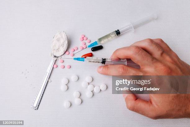 syringe in the hand. hard drugs on the white textile background. lighter and syringe. white textile background. - amphetamine photos et images de collection