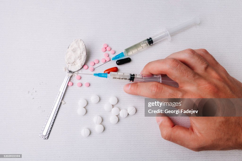 Syringe in the hand. Hard drugs on the white textile background. Lighter and syringe. White textile background.