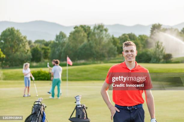 man with friends playing golf on golf course in background - golf sport foto e immagini stock