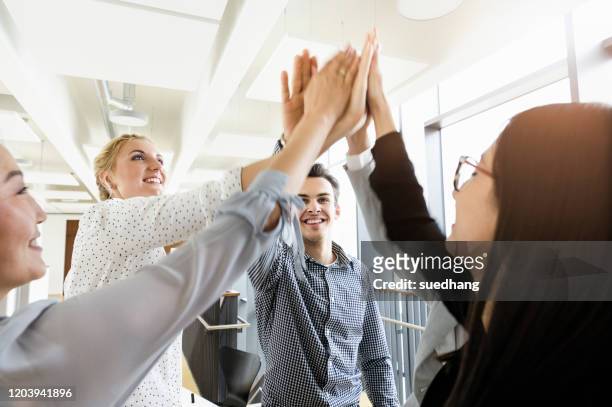 colleagues giving high five in office - cinco pessoas imagens e fotografias de stock
