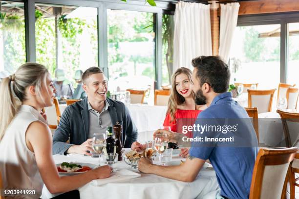 friends talking at dining table in restaurant - four people foto e immagini stock