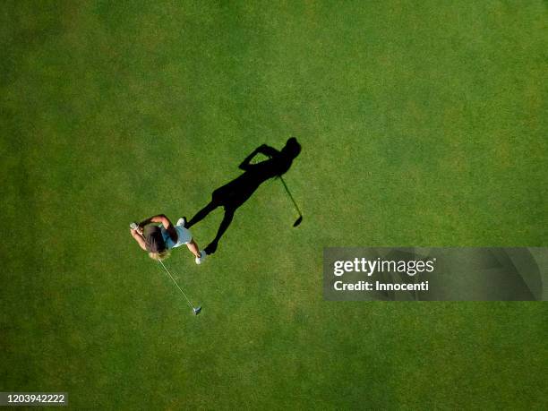 woman playing golf on golf course - women's golf stockfoto's en -beelden