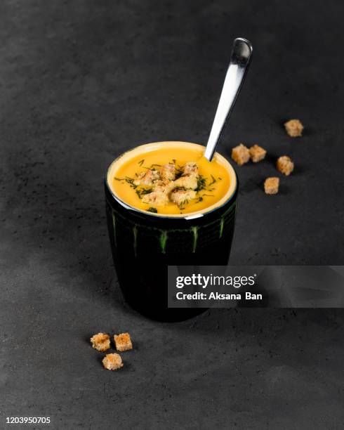 pumpkin soup puree with cream and croutons in a cup on a dark background - crouton stockfoto's en -beelden