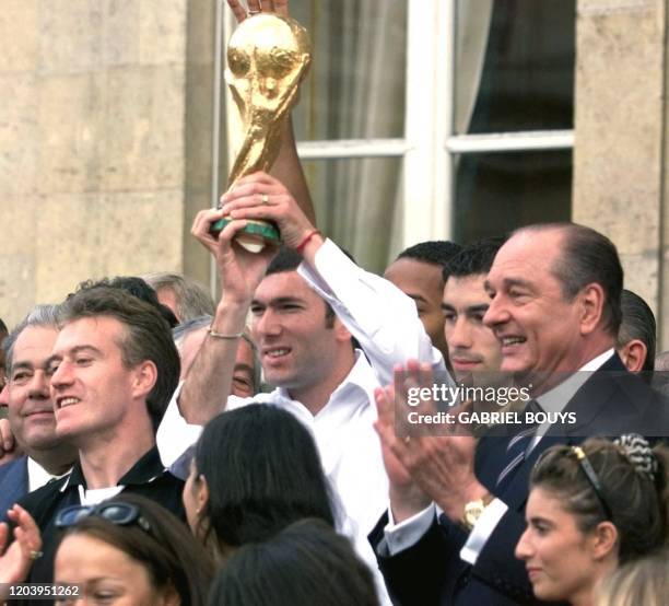 Le meneur de jeu de l'équipe de France de football, Zinedine Zidane, brandit la coupe du monde remportée le 12 juillet, sous les yeux du président...