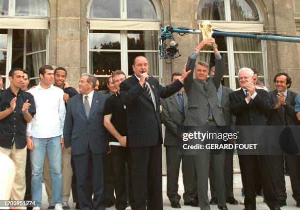 L'entraîneur de l'équipe de France de football, Aimé Jacquet , brandit la coupe du monde remportée le 12 juillet, sous les yeux du président Jacques...