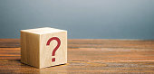 Wooden block with a question mark. Asking questions, searching for truth. Riddle mystery, investigation and research. FAQ - frequently asked questions. Search for information. Q&A