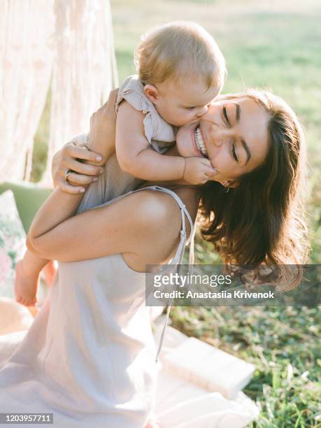 closeup portrait of mother and little daughter playing together in a park. a nice girl and her mother enjoy summertime. - baby sommer stockfoto's en -beelden