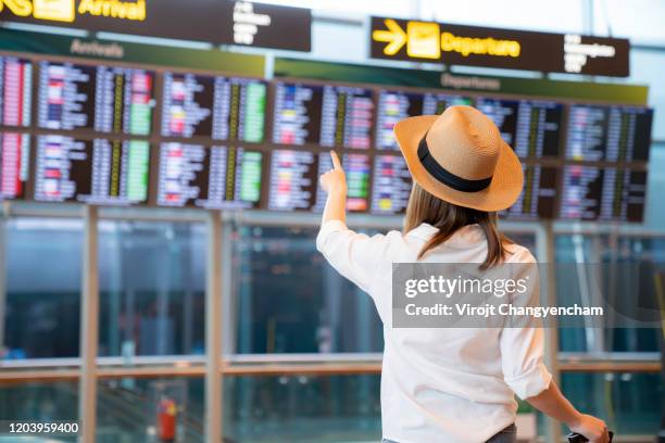 female passenger looking flight schedule on the digital board in the terminal - transfer image stock pictures, royalty-free photos & images