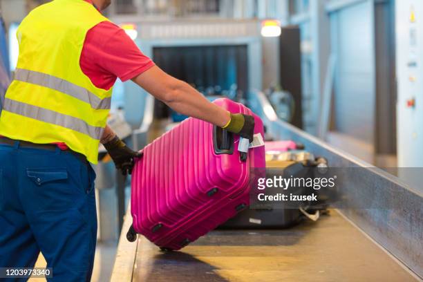 equipo de servicio aeroportuario descargando equipaje - zona de equipajes fotografías e imágenes de stock
