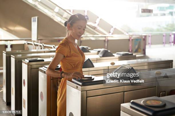 mature woman using mobile phone at turnstile - 改札 ストックフォトと画像