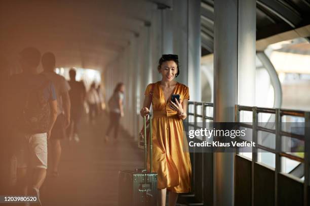 woman using mobile phone at railroad station - orange dress fotografías e imágenes de stock