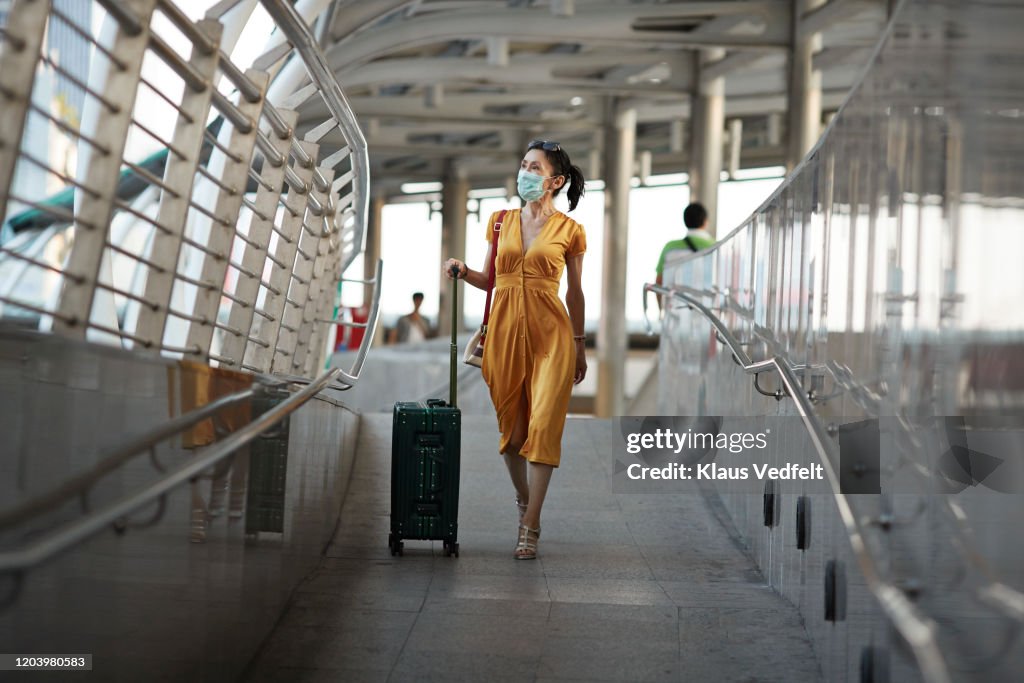 Woman walking with luggage at railroad station