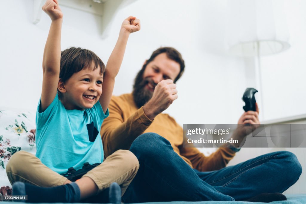 Father and son playing video games at home