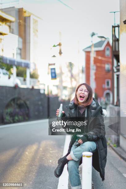 a young woman sitting by the street and smiling - harajuku tokyo harajuku street fashion stock pictures, royalty-free photos & images