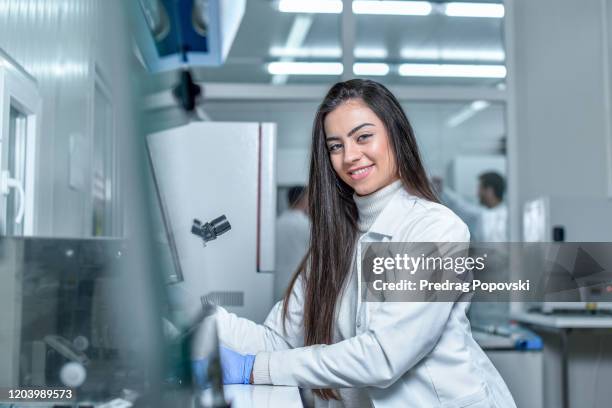 portrait of young beautiful happy female scientist near microscope in laboratory - microbiologist fotografías e imágenes de stock