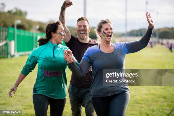 muddy vänner vinkar vid målgång välgörenhet springa - happy ending bildbanksfoton och bilder