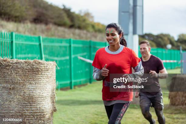 cheerful woman running outdoors in stampede race - charity benefit stock pictures, royalty-free photos & images