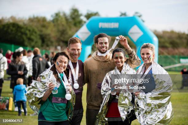 freunde lächeln mit medaillen nach charity-lauf - fundraising stock-fotos und bilder