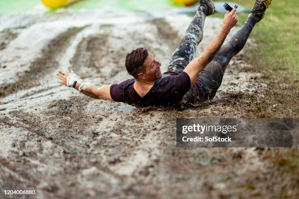 man coming down muddy slip and slide on back - backyard water slide stock pictures, royalty-free photos & images