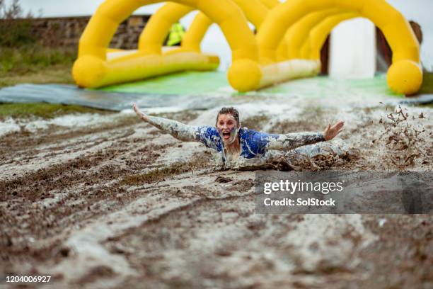 woman splashing down on muddy slip and slide - backyard water slide stock pictures, royalty-free photos & images