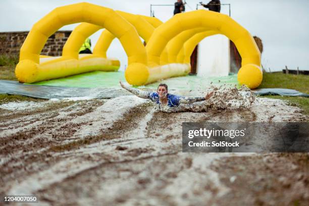 woman having fun on muddy slip and slide - mudslides stock pictures, royalty-free photos & images