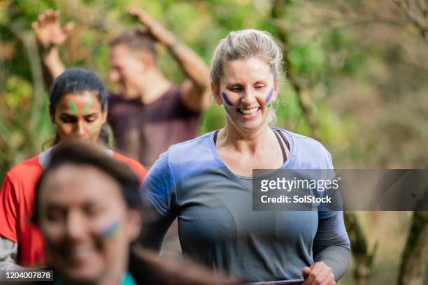 muddy mujer sonriendo en carrera de caridad de campo a través - cross country running fotografías e imágenes de stock