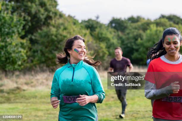 mujeres muddy corriendo a través del país para evento de caridad - cross country running fotografías e imágenes de stock