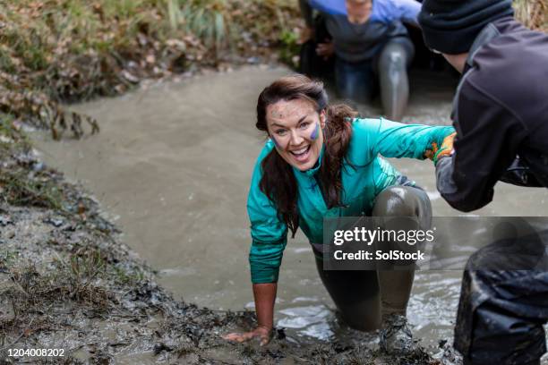 vrolijke vrouw die uit modderig zwembad wordt geholpen - survivor stockfoto's en -beelden