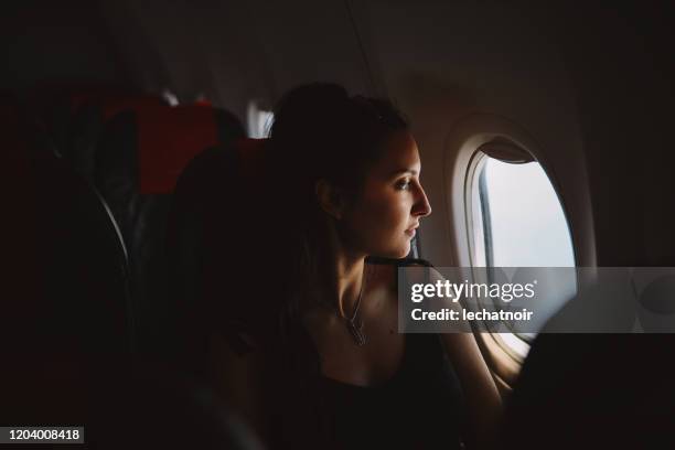 woman in the plane looking through the window - plane window stock pictures, royalty-free photos & images