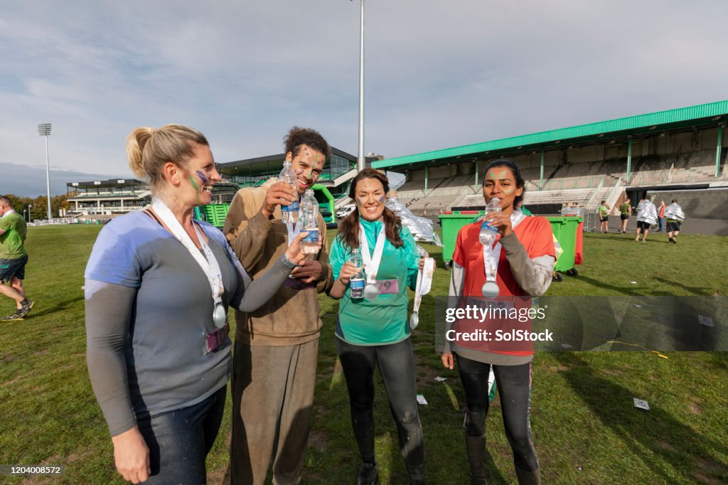 Runners with medals drinking water in sports field after race
