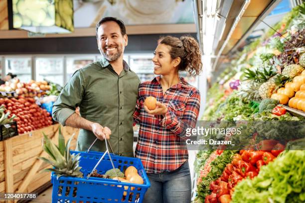 latino paar dat veganistisch voedsel koopt - couple shopping in shopping mall stockfoto's en -beelden