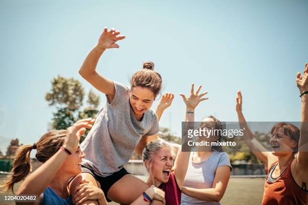 female soccer players celebrating victory on soccer field - sport imagens e fotografias de stock