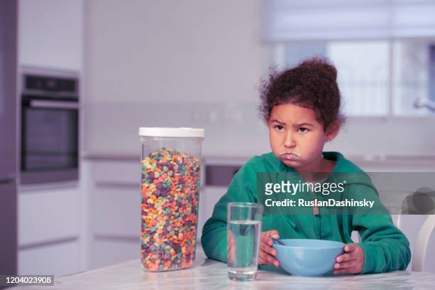 hungry girl eating cereal for breakfast. - eating cereal stock pictures, royalty-free photos & images