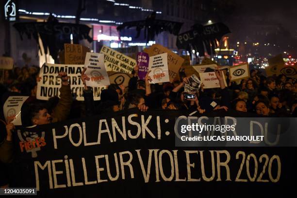 Feminist activists hold a banner reading "Polanski: Best rapist 2020 award" during a demonstration outside the Salle Pleyel in Paris as guests arrive...