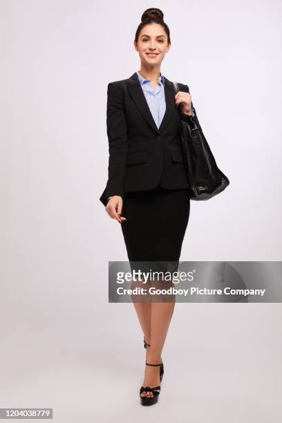 lächelnde geschäftsfrau im anzug, die vor grauem hintergrund läuft - skirt suit stock-fotos und bilder