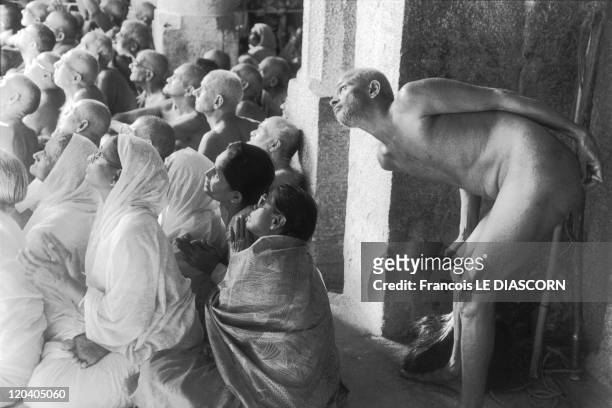 Shravanabelagola, India in 2006 - Naked Jain monk looking at the statue of Bahubali behind a group of women at Karnakata, during the ceremony of...