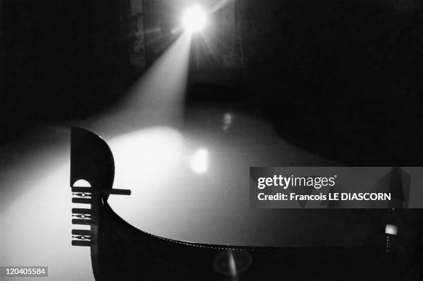 Silhouette of a gondola in a canal at night in Venice, Italy - Silhouette of a gondola in a canal at night, illuminated by lamplight.