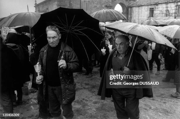 Gralhas, Portugal - The day of Halloween, the output of the church procession to the cemetery on a rainy day, men hold candles and wearing an...