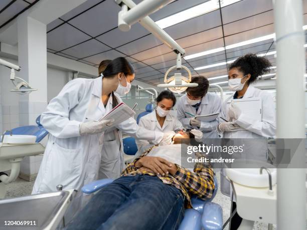 groupe d’étudiants à l’école dentaire observant un dentiste examinant un patient - dental health photos et images de collection