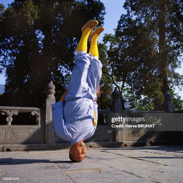 Henan in Shaolin, China - The monk Shi Yan Zheng on the temple terrace executing a very advanced variant of tongzi gong: the posture on the head...