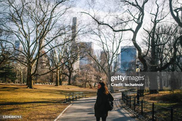 junge frau zu fuß im nyc central park - central park winter stock-fotos und bilder