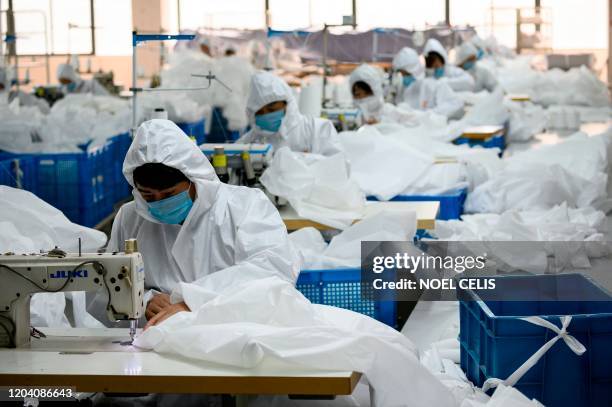 This photo taken on February 28 shows workers sewing at factory making hazardous material suits to be used in the COVID-19 coronavirus outbreak, at...