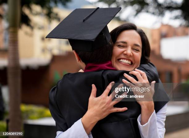 trotse moeder die haar graduatiezoon koestert - graduates stockfoto's en -beelden