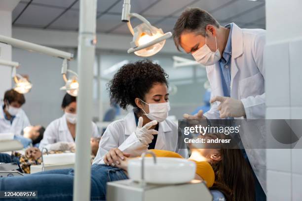 teacher supervising a student examining a patient at dental school - higiene dental imagens e fotografias de stock