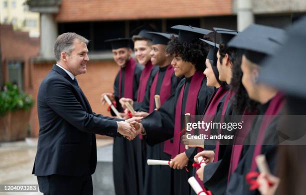 headmaster handshaking with a group of students on their graduation day - dean stock pictures, royalty-free photos & images