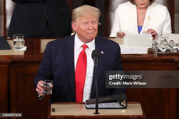 President Donald Trump holds a glass of water during the State of the Union address as House Speaker Rep. Nancy Pelosi and Vice President Mike Pence...