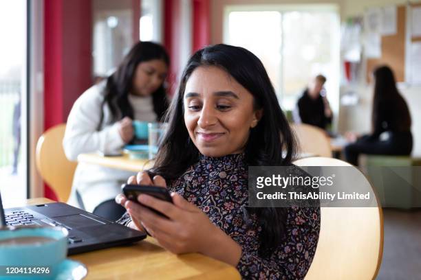 smiling woman using smartphone in cafe - disabilitycollection stock pictures, royalty-free photos & images