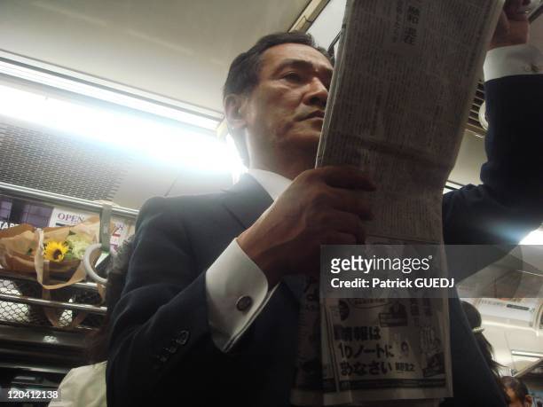 Metro in Tokyo, Japan - Near Shinjuku; Yamanote line, man reading a newspaper.
