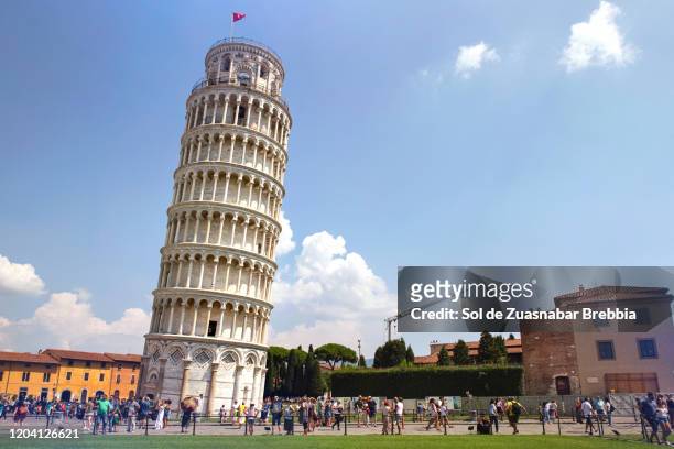 piazza dei miracoli with the leaning tower of pisa surrounded by tourists on a bright sunny day - leaning tower of pisa stockfoto's en -beelden
