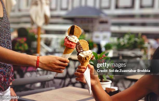 close-up of two hands holding delicious ice creams that come together as a toast - kin in de hand stock-fotos und bilder